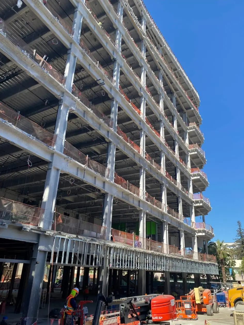 Multi-storey building under construction with fire sprinkler drops visible on every floor.